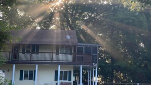 A two-story building with a balcony, surrounded by trees and a gravel driveway. - 669 Rainbow Landing Dr (Cotter)