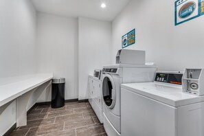Une buanderie équipée d’un lave-linge, d’un sèche-linge et d’une poubelle.