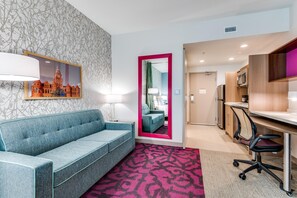 Une chambre d’hôtel équipée d’un canapé, d’un bureau, d’une chaise, d’un miroir et d’un tapis à motifs.