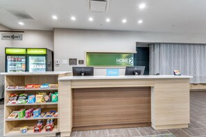 Un espace d’accueil d’hôtel comprenant un comptoir, des distributeurs automatiques et des étagères remplies de collations.