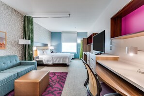 Une chambre d’hôtel avec un lit, un canapé, un bureau et une télévision.