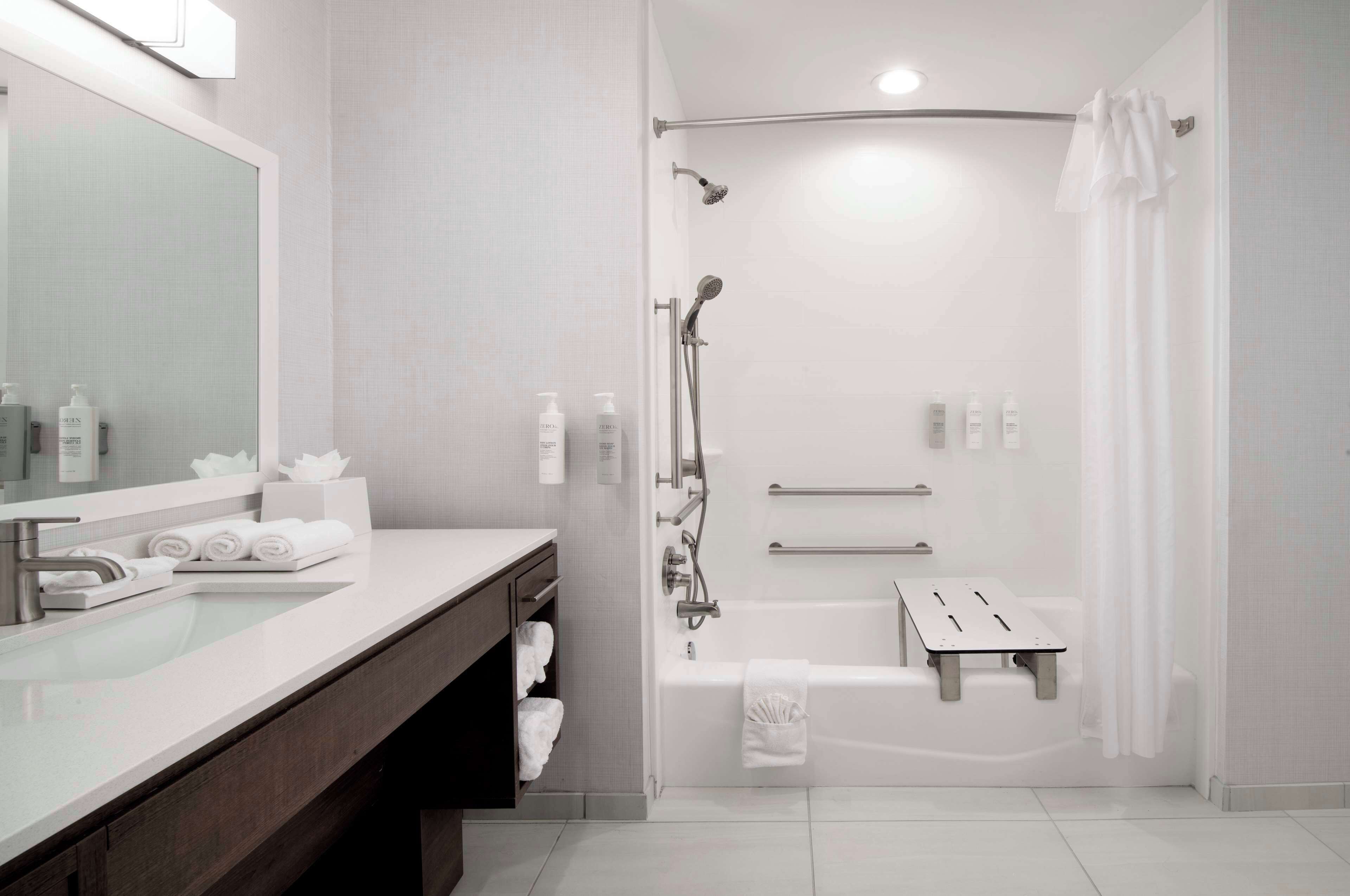 A modern bathroom with a glass-enclosed shower, a vanity with a mirror, and a bathtub.