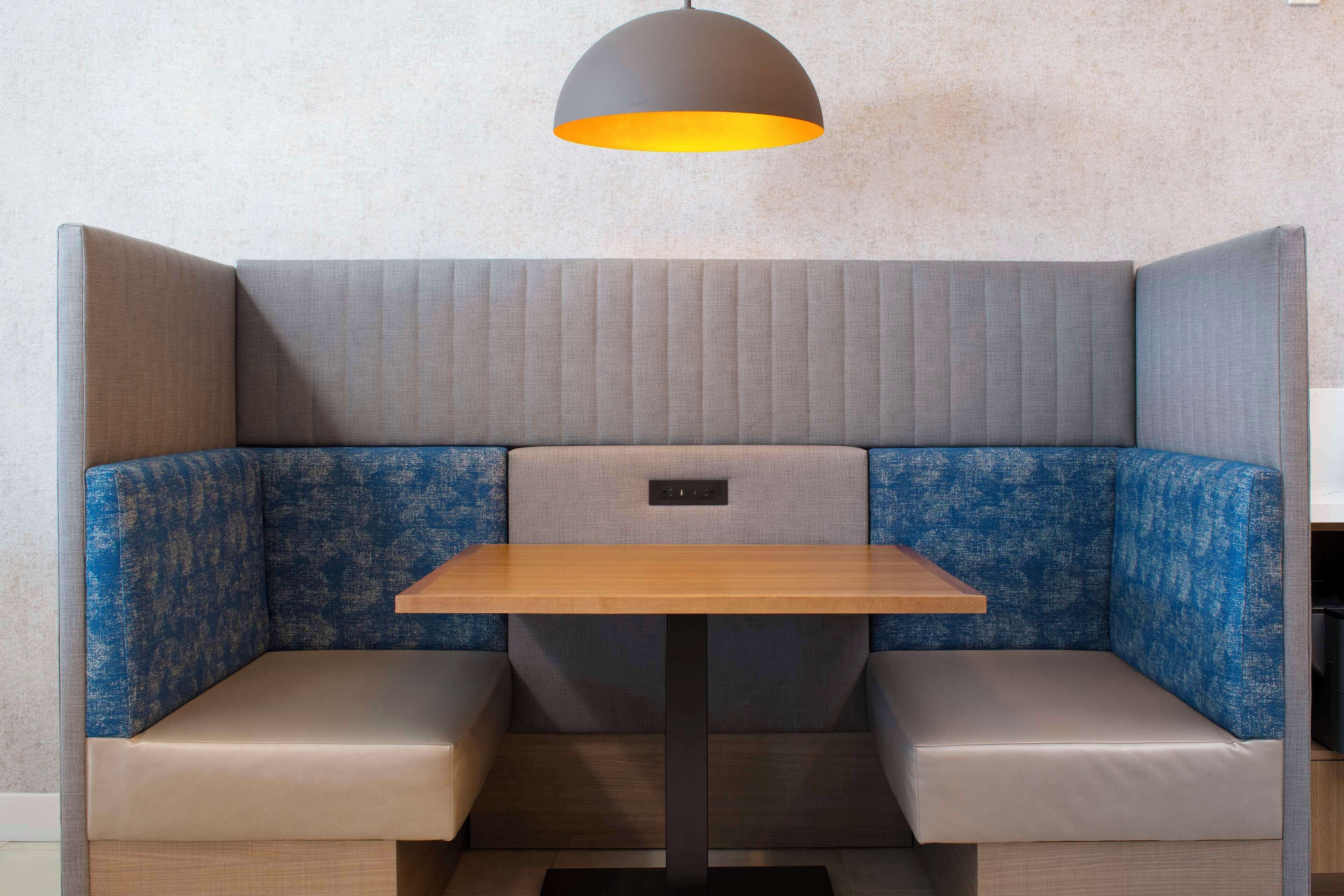 A corner booth with a wooden table and cushioned seating.