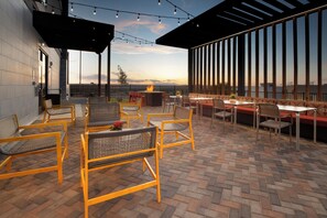 An outdoor patio with seating, a fire pit, and a view of the sunset. - Home2 Suites By Hilton Albuquerque Airport (Albuquerque)