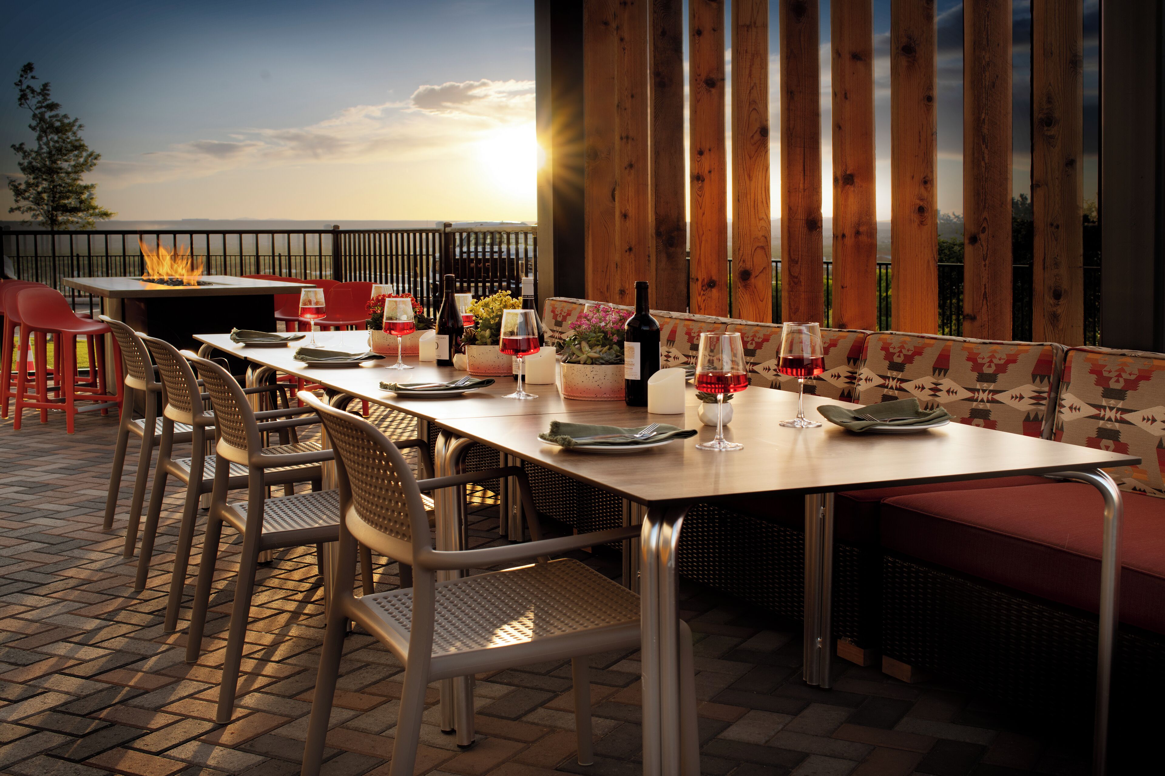 An outdoor dining area with a long table, chairs, and a fire feature.
