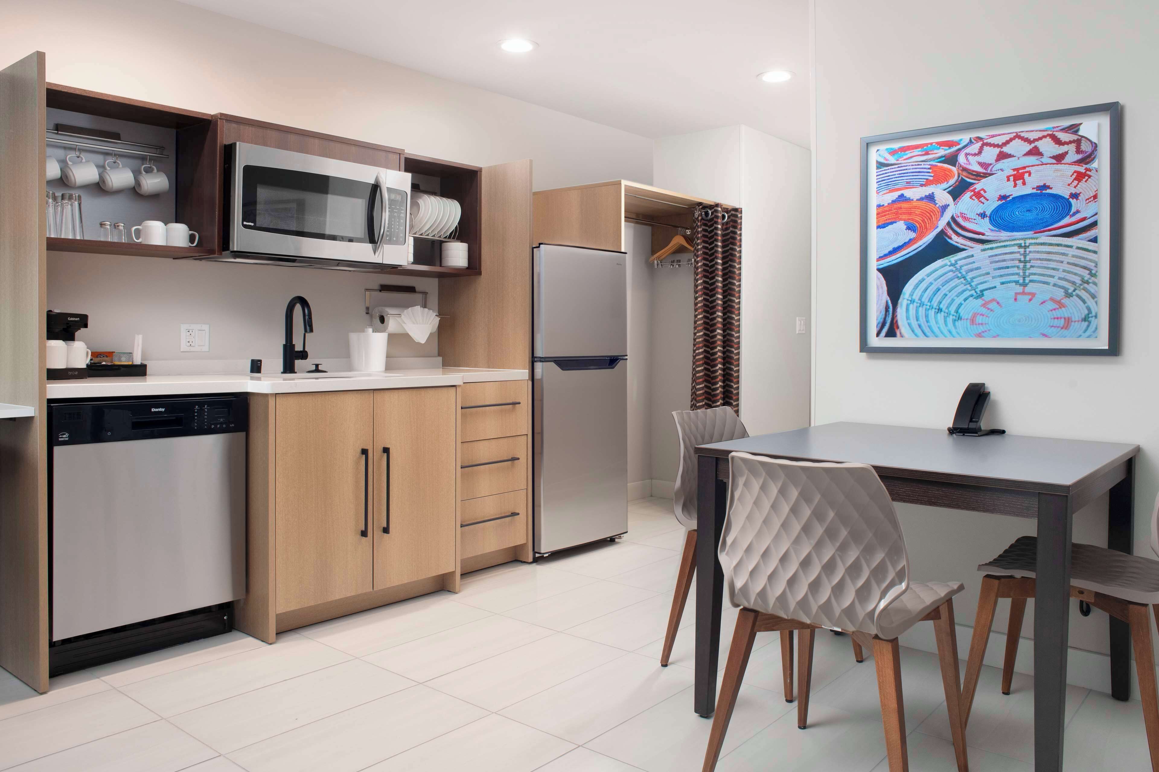 A modern kitchen with a dishwasher, microwave, refrigerator, and wooden cabinets.