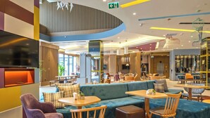 A modern lounge area with seating arrangements, tables, and a TV screen. - Hampton By Hilton Sakarya (Serdivan)