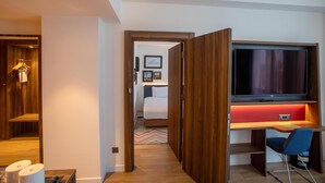 A hotel room with a wooden desk, a television, a bed, and a wardrobe. - Hampton By Hilton Sakarya (Serdivan)