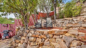 Une terrasse en pierre avec deux chaises, un barbecue et une clôture rouge.