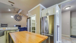Una cocina moderna con una isla de madera, electrodomésticos de acero inoxidable y un ventilador de techo.