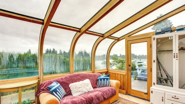 Ein gemütliches Zimmer mit einer hölzernen Bank, einem gepolsterten Sofa mit Kissen und einem Schrank mit Angelruten.