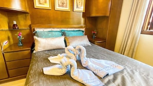 Ein Hotelzimmer mit einem Bett, zwei Nachttischen, einer Blumenvase und einem Fenster mit Vorhängen.