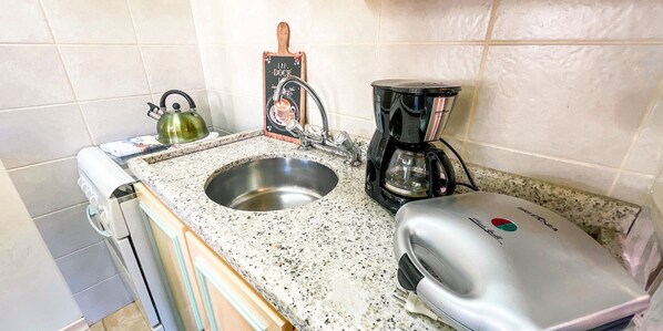 A kitchen with a stainless steel sink, a kettle, a coffee maker, and a toaster. - Requinte e Sofisticação -Monte Belo Flat (Gramado)