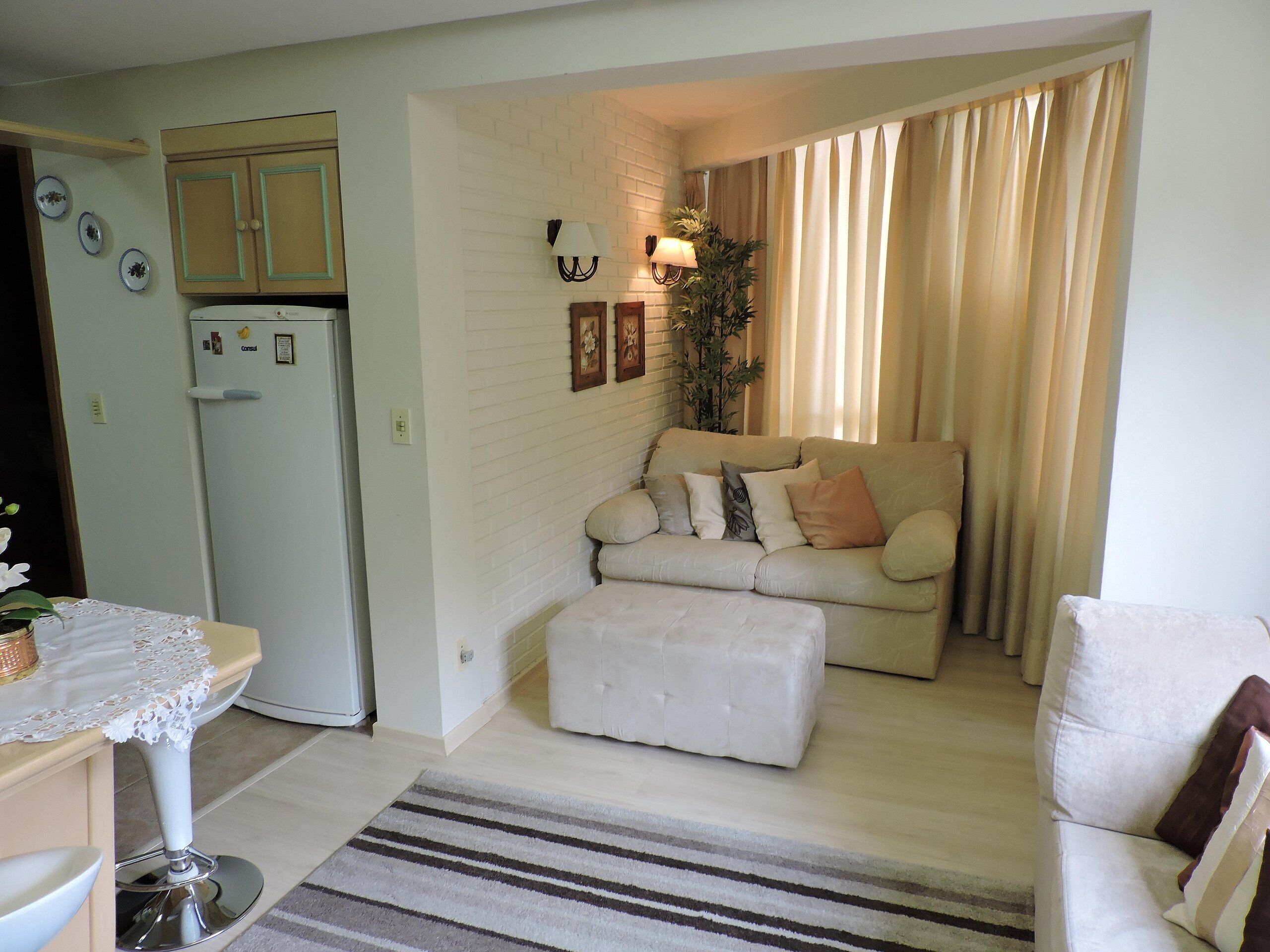 A compact living space with a kitchenette, a sofa set, a dining table, and a decorative plant.