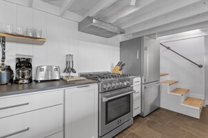 Una cocina moderna con electrodomésticos de acero inoxidable, armarios blancos y encimera de madera.