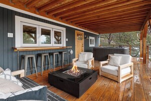 Un espacio al aire libre cubierto con una chimenea, taburetes de bar y dos sofás.