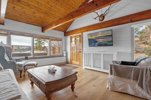 Un salón amplio con techo de madera, ventanas grandes, chimenea y vistas al exterior.