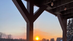 Puinen terassi, jolta avautuu näkymä lumiseen maisemaan ja auringonlaskuun.