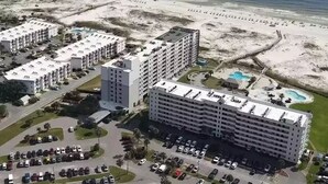 Ett hotell vid kusten med flera byggnader, en parkeringsplats och ett område med strand och en swimmingpool.