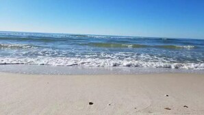En strand där vågorna försiktigt skvalpar mot stranden under en klar himmel.