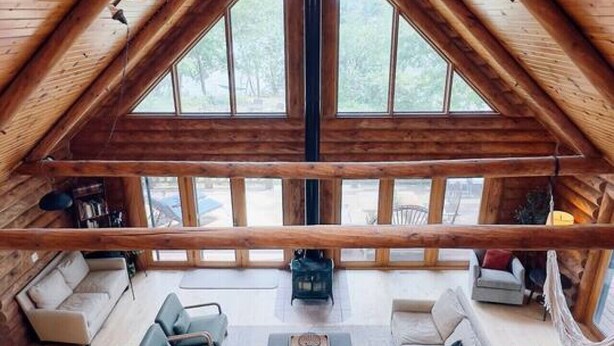 A spacious loft bedroom with a high ceiling, large windows, and a cozy seating area.