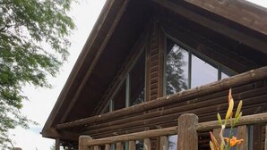 A wooden cabin with a porch and large windows.
