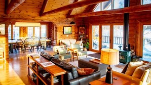 A cozy log cabin interior with a living room, dining area, and a fireplace.