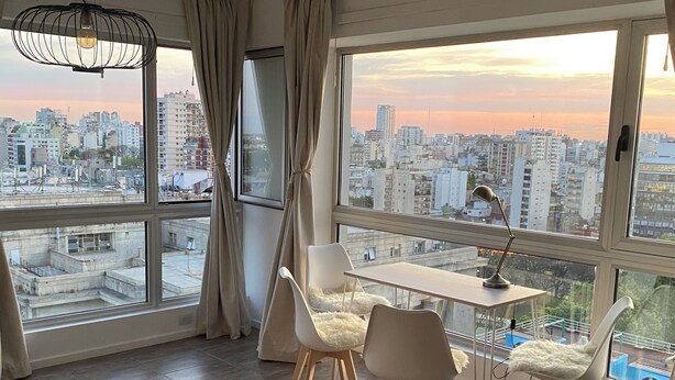 A modern room with a large window, a dining table with chairs, and a desk with a lamp. - QUARTIER  MADERO  (Buenos Aires)