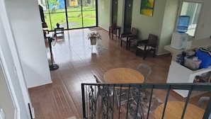 A spacious living area with a large sliding glass door leading to a balcony, a dining table with chairs, and a water dispenser on a stand. - Hotel Pentaqua (Irosin)