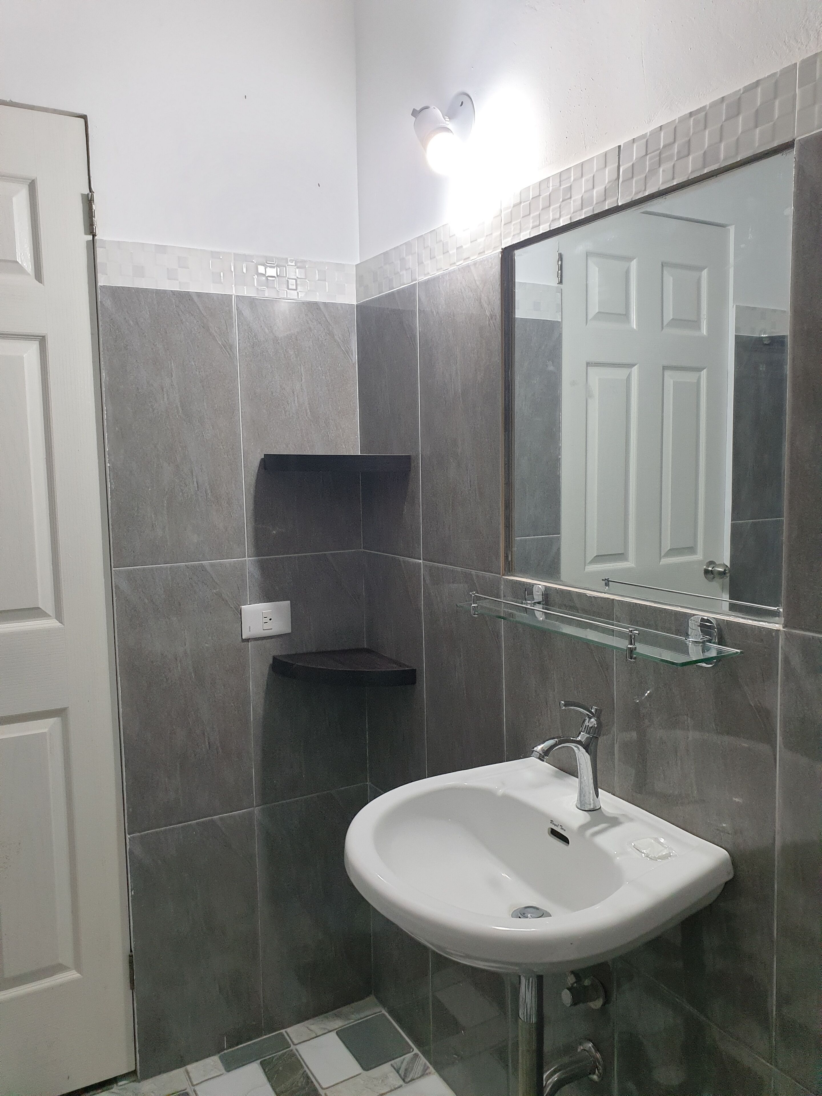 A bathroom with a white sink, a glass shelf, and a mirror above it.
