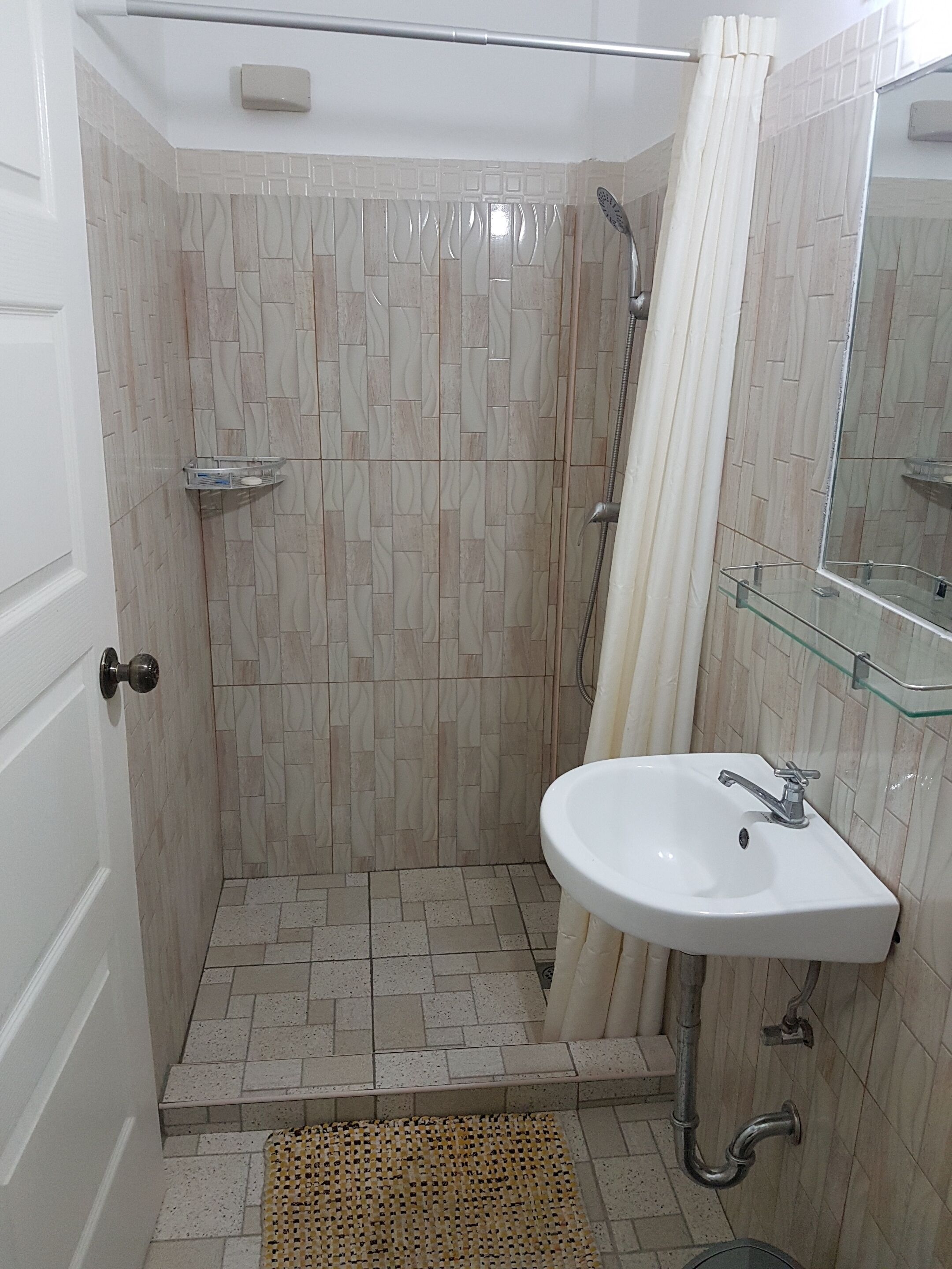 A bathroom with a shower, a sink, and a mirror.