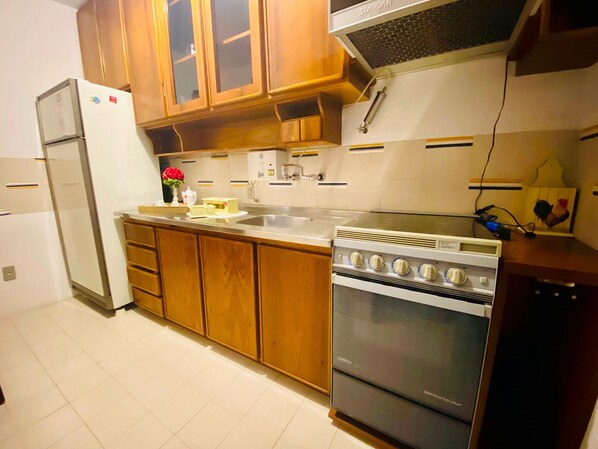 Une cuisine avec des meubles de rangement en bois, un réfrigérateur en acier inoxydable, une cuisinière et un évier.