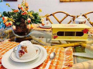 A dining table with a floral centerpiece, a teapot, and a box with a floral design. - EXCELENTE OPÇAO - 03 quadras RUA COBERTA (Gramado)