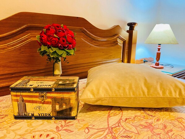 A bed with a wooden headboard, a bedside lamp, a vase with red roses, and a vintage suitcase with "NEW YORK" on it. - EXCELENTE OPÇAO - 03 quadras RUA COBERTA (Gramado)