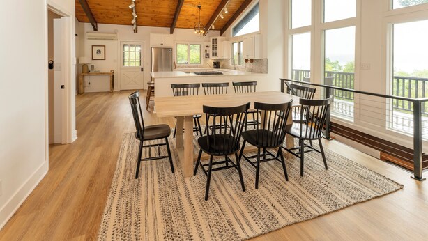 A spacious kitchen with a large island, wooden ceiling beams, and large windows offering a view. - Enjoy Cabin Vibes & Lake Views, Close to Town, Lake & FLX Activities; EV Charger (Canandaigua)