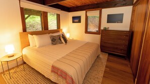 A bedroom with a bed, bedside lamps, a dresser, and a window with a view of greenery. - Enjoy Cabin Vibes & Lake Views, Close to Town, Lake & FLX Activities; EV Charger (Canandaigua)
