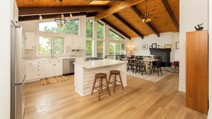 A spacious kitchen with a large island, wooden flooring, and a dining area with a fireplace. - Enjoy Cabin Vibes & Lake Views, Close to Town, Lake & FLX Activities; EV Charger (Canandaigua)