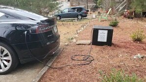 En svart bil stod parkerad bredvid en laddstation, och en skylt visade att den var avsedd för elfordon.