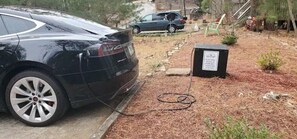 A black car parked next to a charging station with a sign indicating it is for electric vehicles.