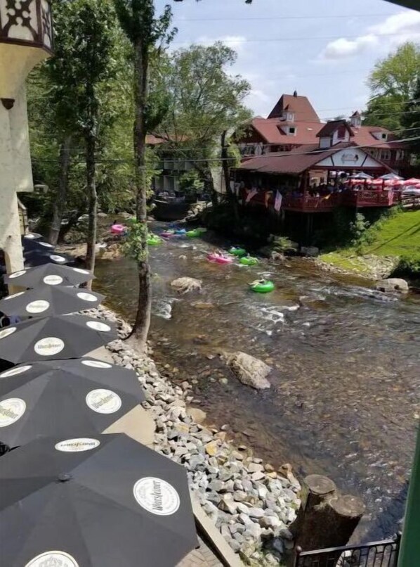 A riverside view with outdoor seating and a restaurant in the background.