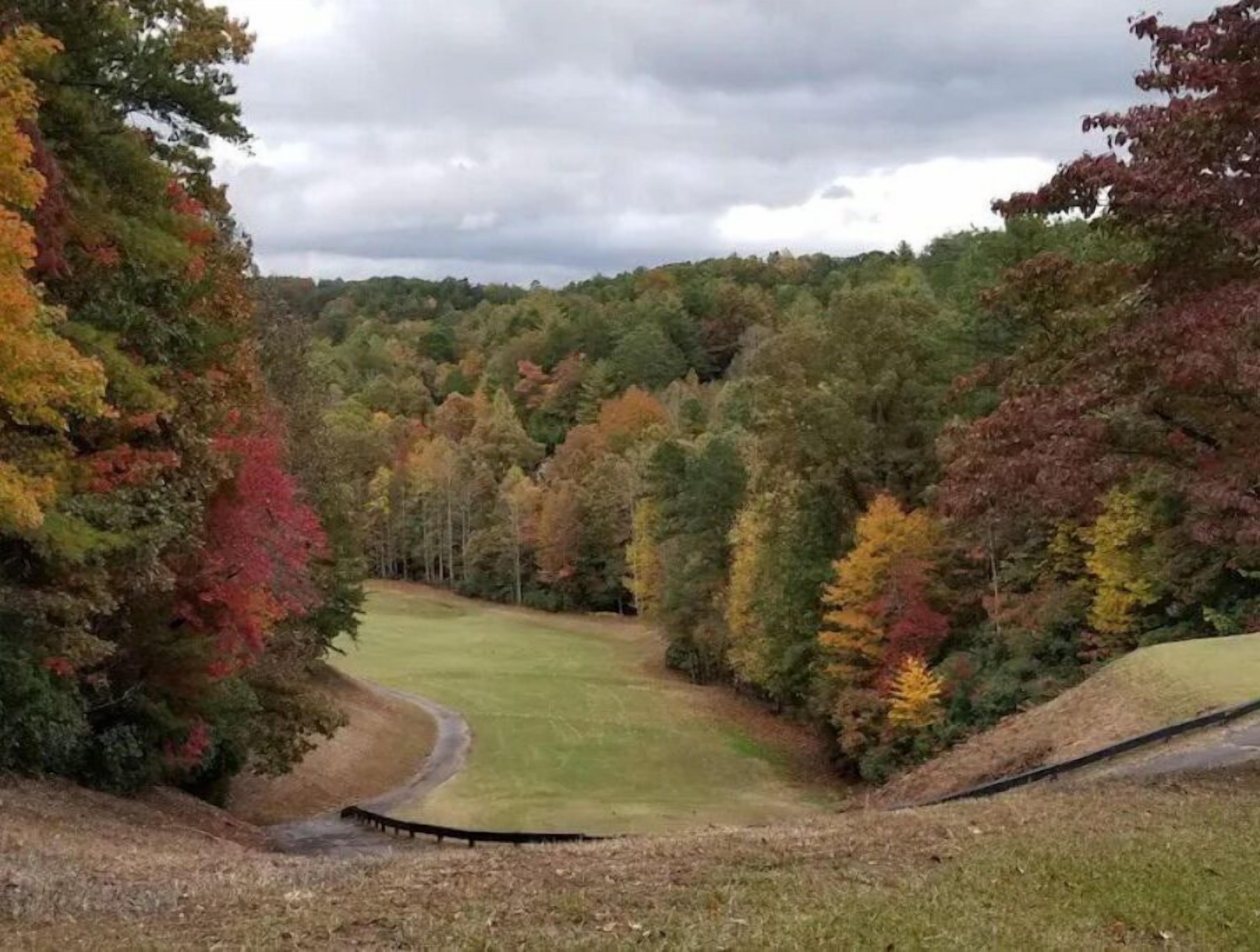 A golf course with a well-maintained fairway and surrounding wooded areas.
