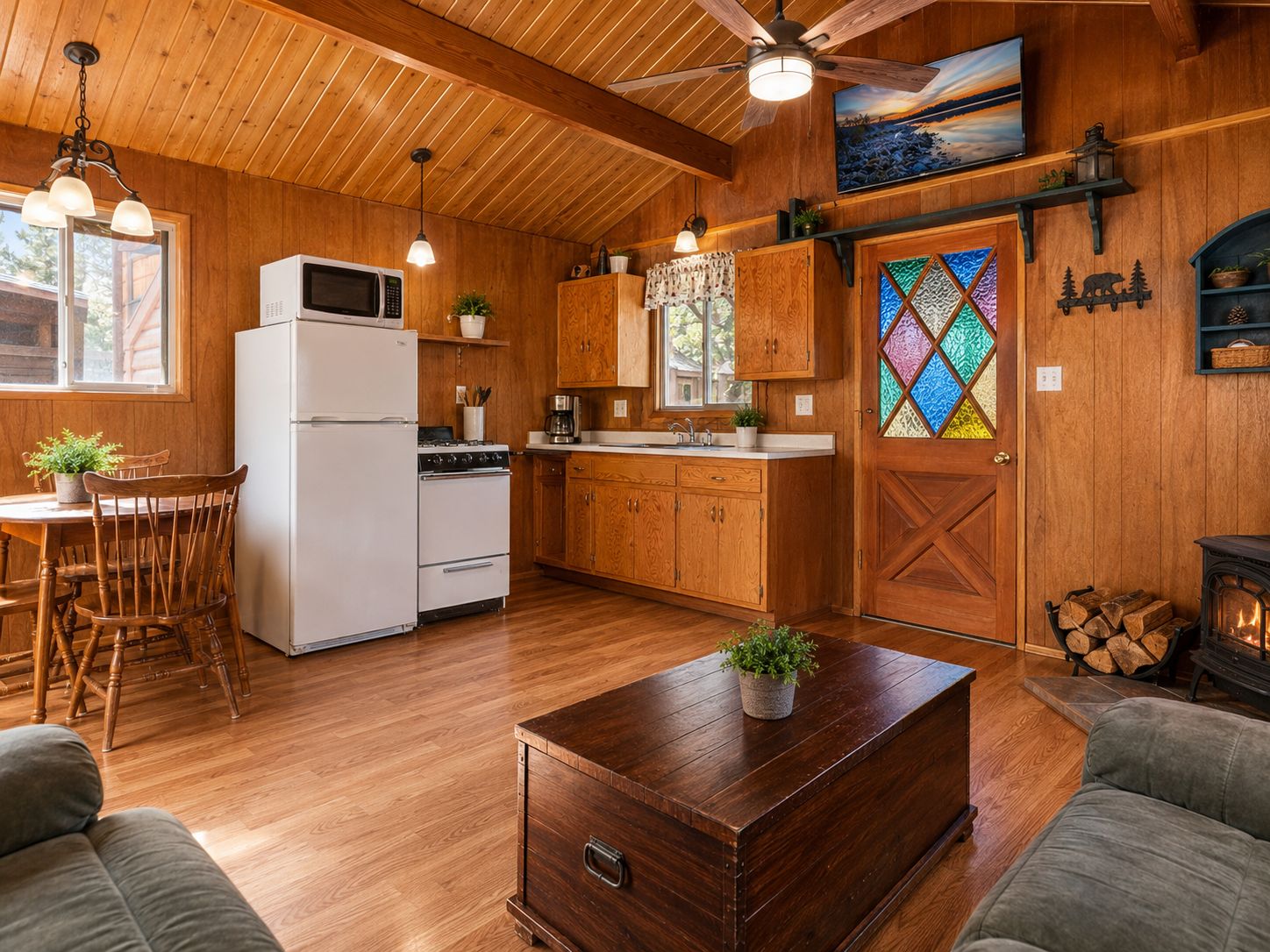 Interior acolhedor de uma cabana, com decoração em madeira, sala de jantar, cozinha e lareira.