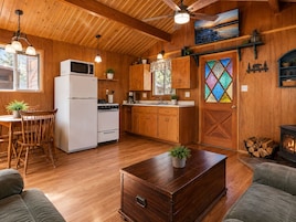 A cozy cabin interior with a wooden interior, a dining area, kitchen, and a fireplace.