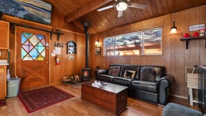 Ein gemütliches Blockhaus-Interieur mit Holzboden, Ledersofa, Couchtisch aus Holz und Kamin.