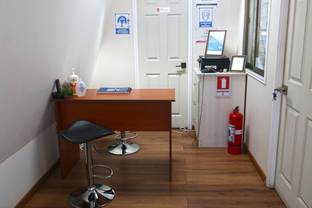 A hallway with a reception desk, a fire extinguisher, and a private door.