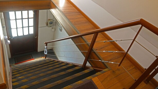 Eine Holztreppe mit Metallgeländer und einer Glastür am Obergeschoss.