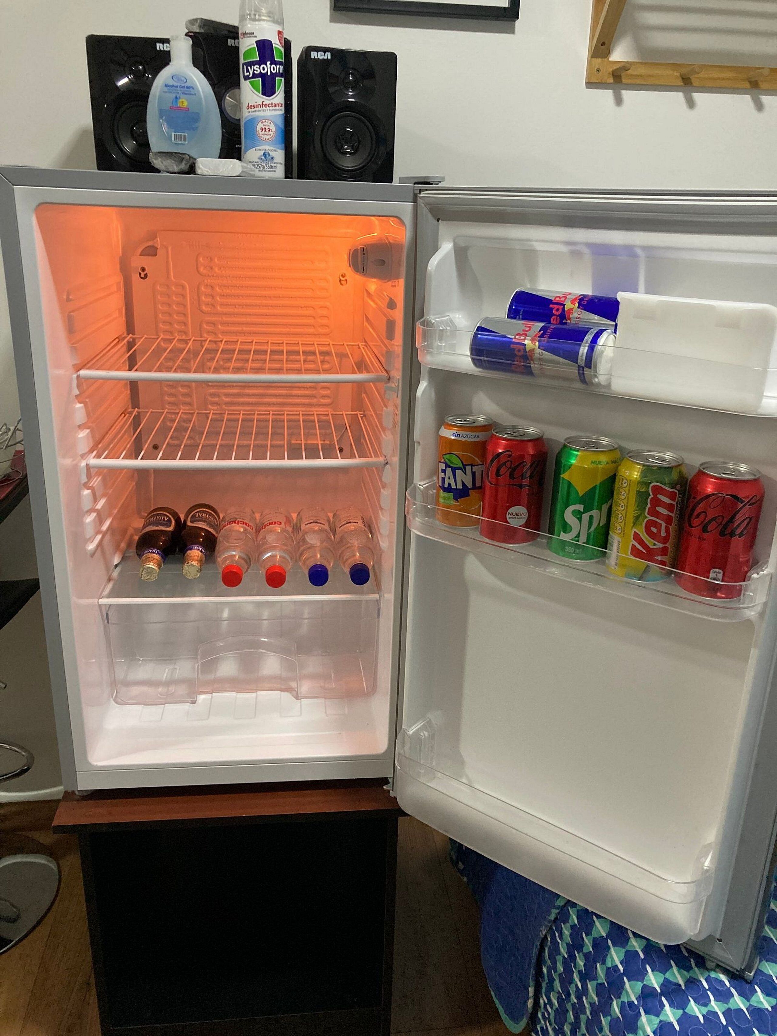 An open refrigerator with shelves containing bottles and cans.