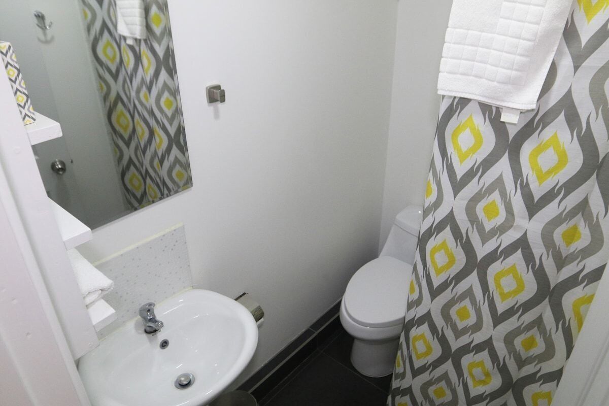 A bathroom with a white sink, mirror, and toilet. The walls have a geometric patterned wallpaper.