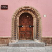 A wooden door with a decorative arch and tiled patterns on the walls.
