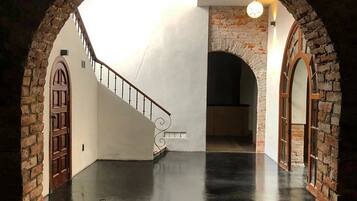 A spacious interior with a polished concrete floor, a staircase with a metal railing, and brick arches framing the space.